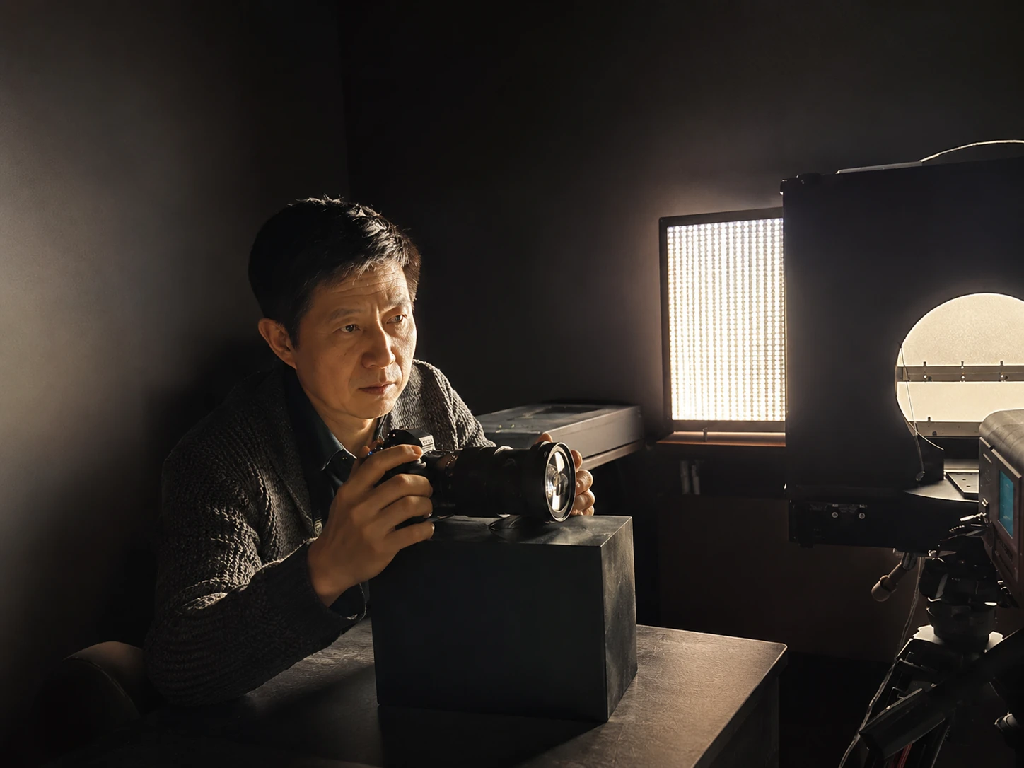 PROMPTERGO chief engineer inspecting an optical component beside a teleprompter